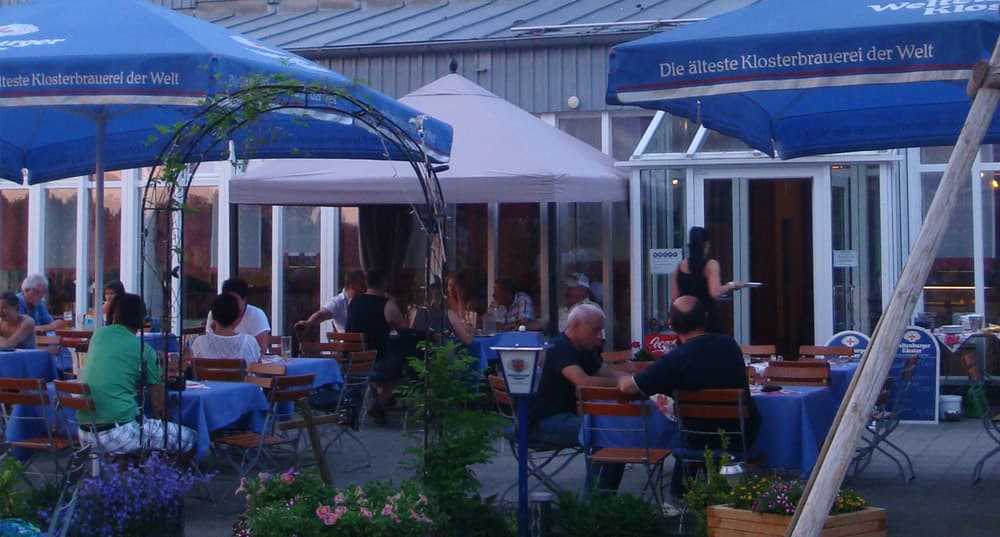 Der schattige Biergarten des Valentinsbads mit blauen Schirmen