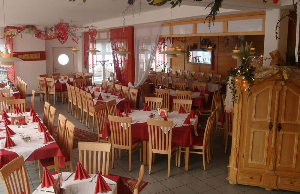 Der helle Gastraum mit eingedeckten Tischen